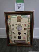 Full view of framed set of Canadian coins and stamps from King George V era, showing all coins, stamps, decorative border and central paper medallion