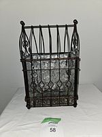 Front angled view of a burnished bronze finished metal lantern with clear textured glass panels, displaying decorative scrollwork and diamond motif on metal cage.