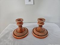 Pair of small vintage Mid-Century Modern candle holders in reddish-brown with decorative ridged bases, showing front and side views
