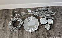 Overview of all items in lot showing wreath, sunburst mirror, set of three round small decorative mirrors, and bunch of six glittery silver branches
