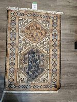 Full view of Kilim rug with animal motifs and neutral colors on a wood floor.