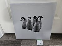 Front view of the wrapped canvas showing the black and white penguin chicks artwork.