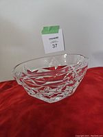 Small cut crystal bowl photographed on red cloth background showing geometric cut design and overall shape.
