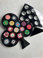 Two black plastic coin display holders shaped like playing card suits with multiple casino chips inserted in circular slots.