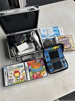 Full view of Nintendo DS, games, accessories, and metal carrying case on table