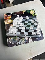 Closed box of the 3-in-1 glass board game set on a table showing frosted and clear glass chess pieces and a glass checkerboard.