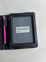 Kobo eReader inside black protective cover case with white stitching and purple stylus pen attached on the left side. Screen displaying 'Scanning for networks' message.