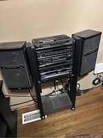 Full view of Yorx stereo system with speakers set up on stands against wall on hardwood floor