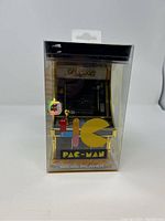 Front view of Pac-Man Micro Player in its clear plastic packaging showing the miniature arcade game design and related artwork.