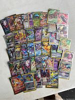 Top-down view of approximately 43 rare Pokemon trading cards spread out on a white surface, showing a variety of holographic and full-art cards from different series.