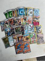 Top-down view of 32 assorted rare Pokemon cards, including Energy, Trainer, and several holographic Pokemon cards.