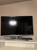 Small RCA flat screen television on white shelf with power cord coiled beside it.