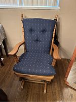 Front view of wooden rocking chair with navy blue cushioned seat and backrest showing fabric pattern and wood details.