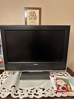 Front view of the Toshiba small TV sitting on a table with decorative items around it. Screen is off.