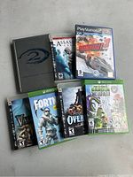 Seven video game cases including six Xbox and one PlayStation 2 game case arranged on a flat surface.