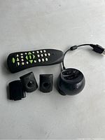 Photo shows Xbox remote control, round charging dock, and two rechargeable battery packs on concrete surface.