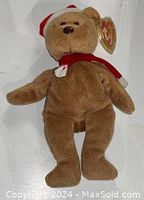Beanie Babies plush bear wearing red and white Santa hat and red scarf, showing front view with attached Ty tag.