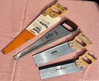 Photo of four hand saws arranged side by side on pink cloth background, showing overall condition and size.
