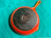 Bottom view of Le Creuset enameled cast iron skillet showing manufacturer markings and size 23 embossed in the cast iron base.