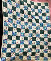 Full view of the quilt showing the checkerboard patchwork pattern of floral and solid prints in various colors.