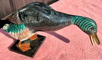 Side view of the vintage leaning mallard duck decoy showing painted detail and standing base.
