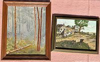 Two framed oil on board paintings, one showing a foggy forest scene and the other a rural landscape with houses and a large tree.