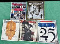 Five vintage Rolling Stone magazines laid out on green cloth background, showing colorful and distinctive covers from early 90s and 2000s.