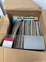 Open cardboard box filled with craft magazines including labeled sections for plastic canvas and Christmas/Holiday themes.