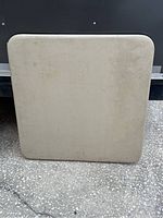 Top surface of beige folding card table with some marks and rounded corners