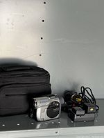 Hitachi DVD camcorder with black carrying case, power cords, battery packs, and charger on surface