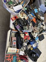 Photo of miscellaneous lot with jumper cables, fishing reel, flashlight, hand tools, books, batteries, and various small household items