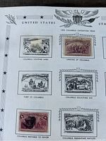 Close-up of album page featuring 1893 Columbus Exposition Issue stamps with detailed illustrations related to Columbus's voyages.