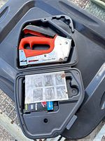 Power Shot Pro stapler resting in its black carrying case along with the instruction manual and staples.