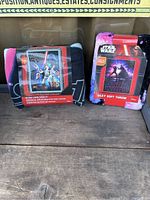Two Star Wars throw blankets in their original packaging displayed side by side on wood surface