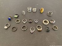 18 sterling silver rings arranged on black background