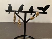 Both pairs of gold earrings displayed on a stand