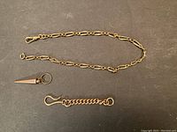 Three components laid out: elongated link chain, conical pendant, short curb-link chain with S-hook