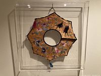 Frontal view of the embroidered silk collar inside a clear 12x12 inch case, showing the overall hexagonal shape and embroidery details.