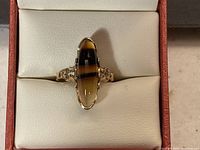 Front view of the antique elongated oval cabochon ring showing black and amber banded stone in 10kt yellow gold filigree setting.