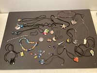 Multiple Murano glass jewelry pieces including necklaces, pendants, bracelets laid out on a flat surface.