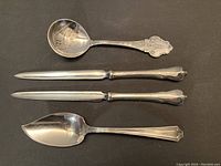 Four sterling silver items displayed on black background consisting of two spoons and two letter openers.