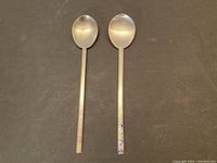 Two vintage Korean silver spoons displayed side by side showing their overall form and handles.