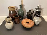 Nine pieces arranged on black mat with ruler behind large pitcher