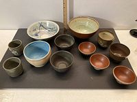 Overview of all 12 bowls arranged on a flat surface showing size range and variety in glazes and styles.