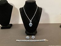 Full jewelry suite displayed on black bust and tabletop