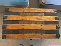 Overhead view of the antique blanket chest top showing wooden slats and fabric panels with metal corner protectors.