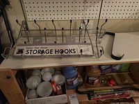 Photo showing over the door storage hooks, one black and white wreath hook, and a box of various lightbulbs underneath the shelf.