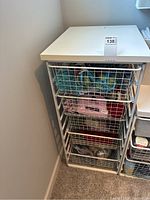 White 5-drawer wire-mesh storage unit with solid top panel showing overall condition and structure near corner wall