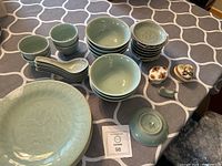 Overview of the sushi dish set including bowls, plates, spoons, two pill boxes, and whale chopstick holder on a patterned tablecloth.