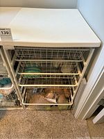 Full view of the white IKEA storage unit with five wire basket drawers containing various yarn skeins.